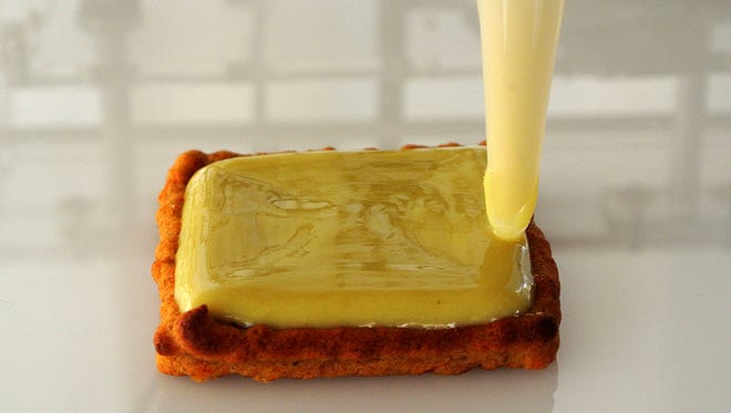 Cheese is added with a 3-D printer to the top of a black bean burger patty. Printers are being compared to the impact of microwaves in the 1970s.