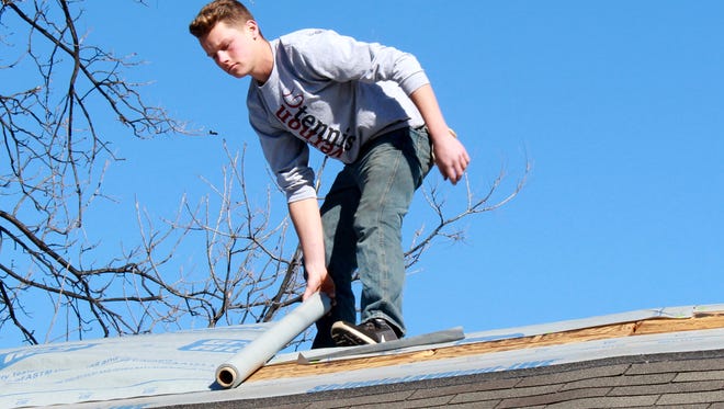 Seventeen-year-old Ethan Curtis works on the roof of one of the homes he chose to receive a new roof as part of a service project designed to show Christian love to members of the community.