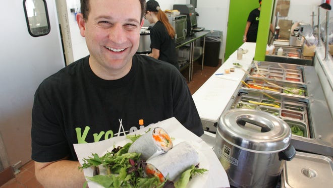 Owner Avi Shafshak holds a sushi burrito made for a customer at his restaurant KreAsian.