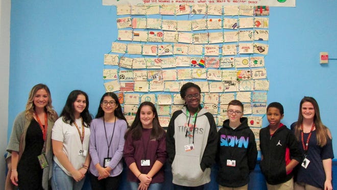 Language arts teachers Jennifer MacDonald (left) and Jamie Pierson (right) with some of their students in front of the “Piece by Peace” quilt that hangs at Soehl Middle School in Linden. From left are Sophia Molina, Fabiana Lopez, Natalia Silva-Miceli, Ezinne Amadi, Jan Zasowski and Jean-Charles Precois.