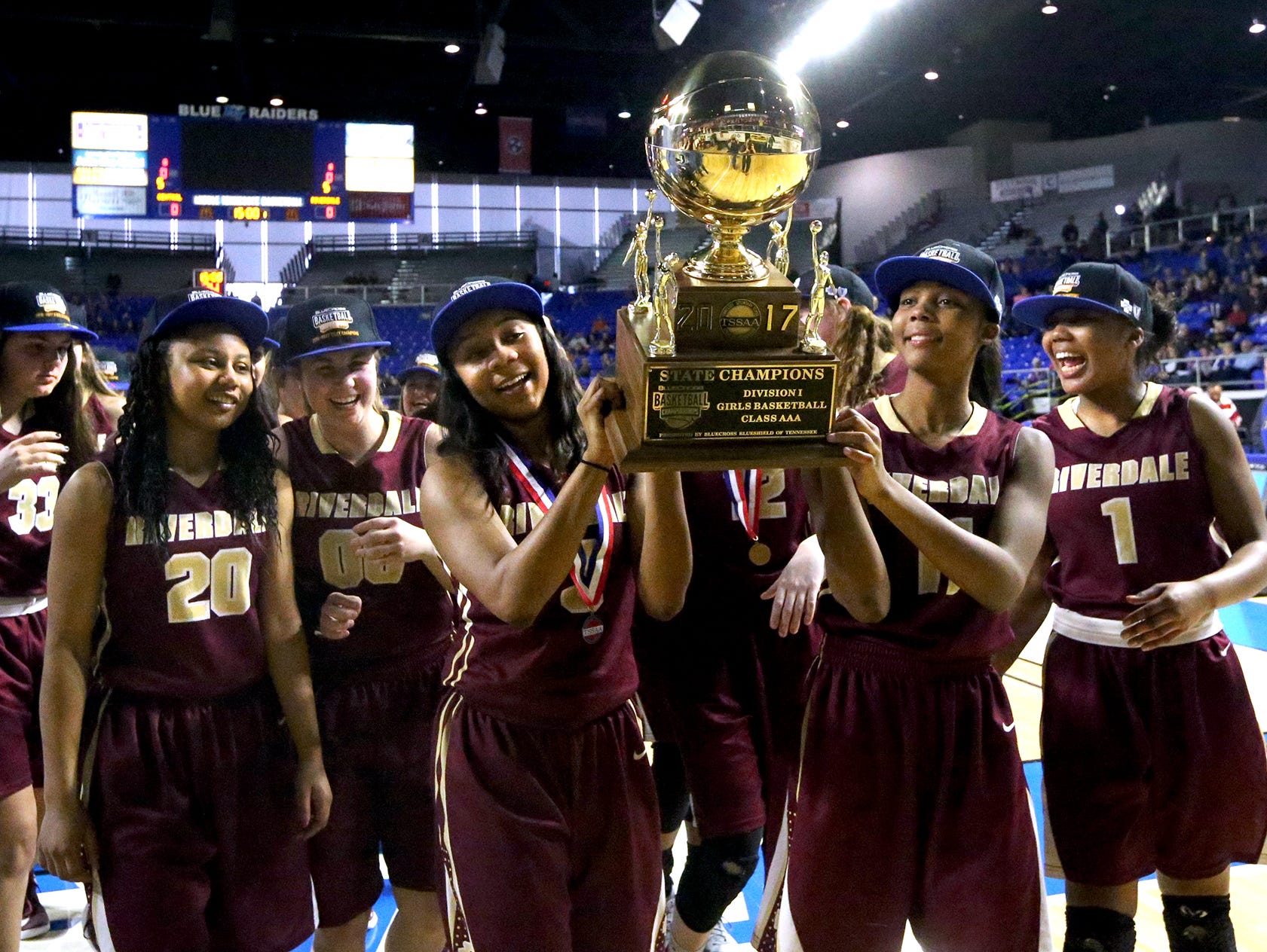 Riverdale's Anastasia Hayes (3) and her sister Aislynn Hayes (11) carry the championship trophy over to the Riverdale fans as the team celebrates its victory over Memphis Central in the Class AAA championship on Saturday, March 11, 2017.