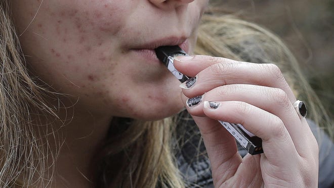 A high school student uses a vaping device near a school campus in Cambridge, Mass. Twice as many high school students used nicotine-tinged electronic cigarettes in 2018 compared with the previous year, an unprecedented jump in a large annual survey of teen smoking, drinking and drug use.