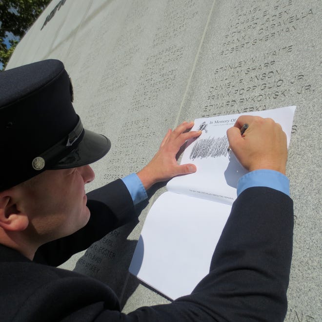 Binghamton firefighter Josh Graupman stencils John Janos’ name at the 17th Annual Fallen Firefighters Memorial Ceremony in Albany.
