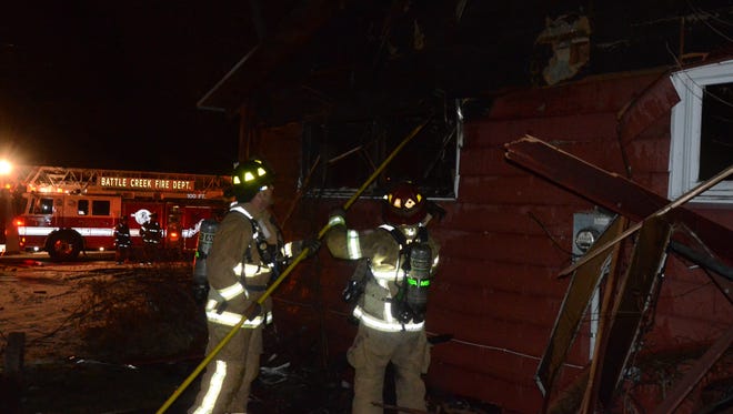 Battle Creek firefighters search for fire in the walls of a house on 21st Street Thursday night.