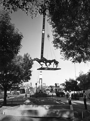 Workers begin to lower the yearlings horse statue into a concrete base.  The base was 1/2 inches too small for the sculpture.