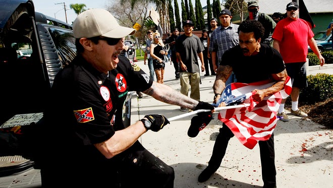 A Ku Klux Klansman, left, fights a counter protester for an American flag after members of the KKK tried to start a "White Lives Matter" rally at Pearson Park in Anaheim on Feb. 27, 2016.