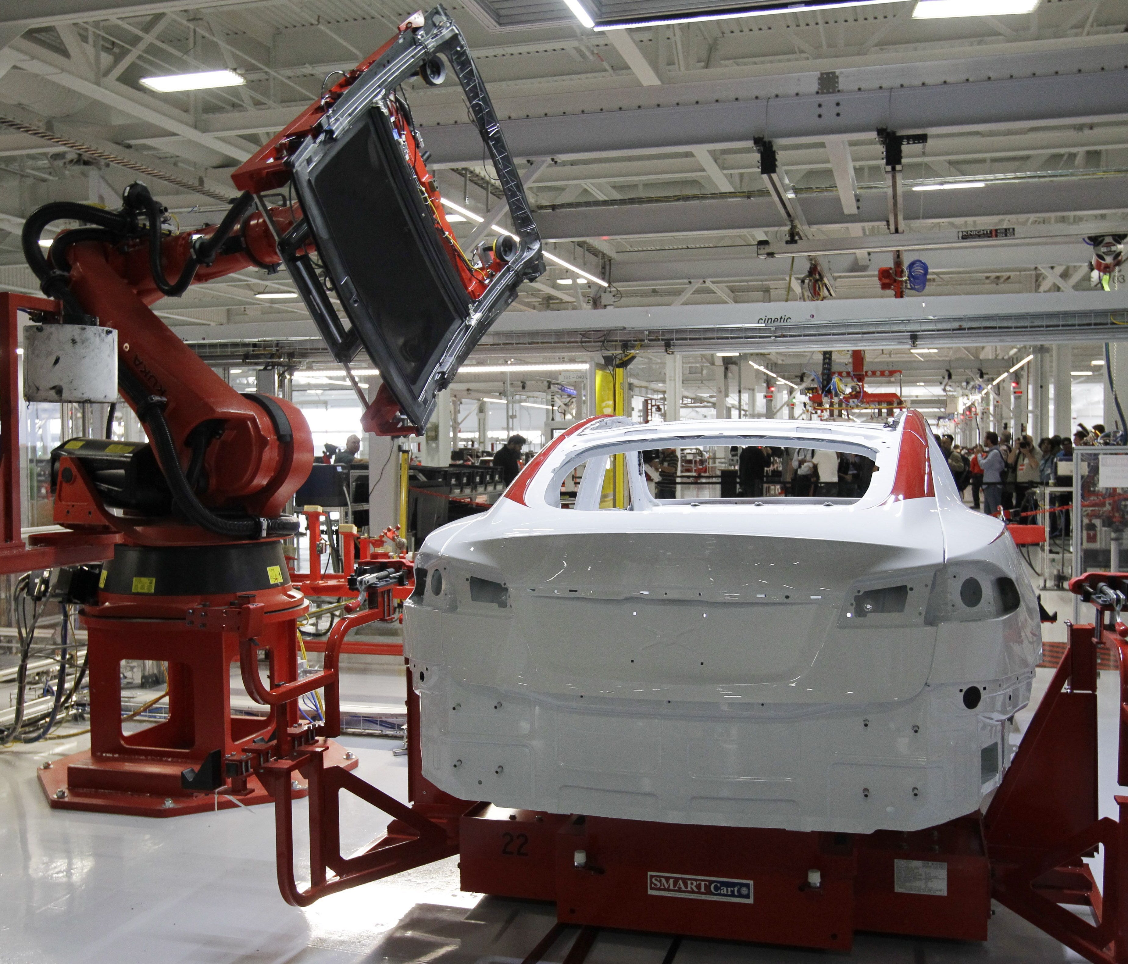 A robot puts on the top of a Tesla Model S at the Tesla factory in Fremont, Calif.