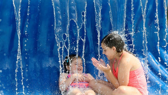 Children play in the water at the Harrison Taylor Splash Pad in Palmore Park in Tuscaloosa Thursday, June 4, 2020. Sisters Addison and Emma Kate Berryhill sit beneath a small waterfall.
