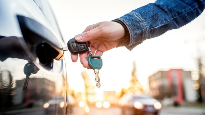 Woman opening her car with a key.