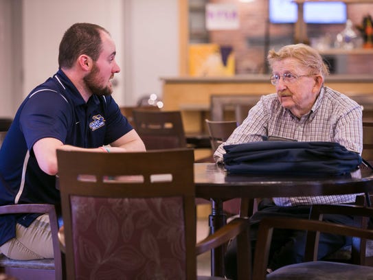 Jeremy Benoit, assistant athletics director at Goldey-Beacom College, talks to a veteran at the at the nearby retirement community, The Summit. Students have been recording the veterans' stories and will be transcribing them and turning them into a book.