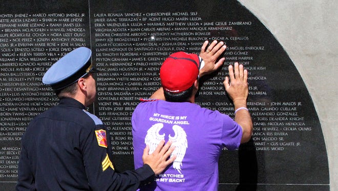 Andres Robles Jr., right, is comforted by El Paso police Sgt. David Cox while he looks at the name of his niece, Shannon Del Rio, on the Crime Victims’ Memorial Reading Garden Pavilion in 2016.