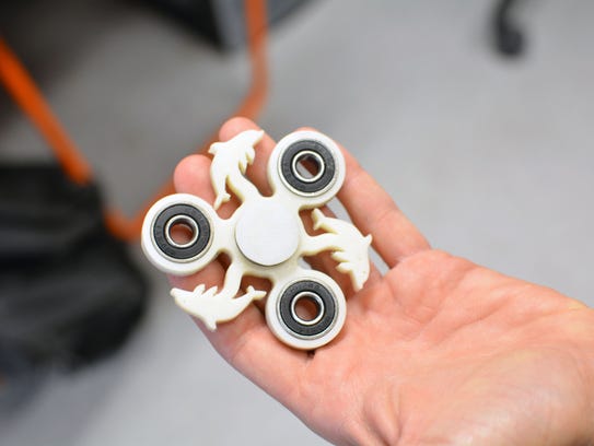 Tom Burick holds a 3-D-printed fidget spinner created