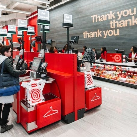 The interior of a Target store where customers are standing at self-checkout kiosks.
