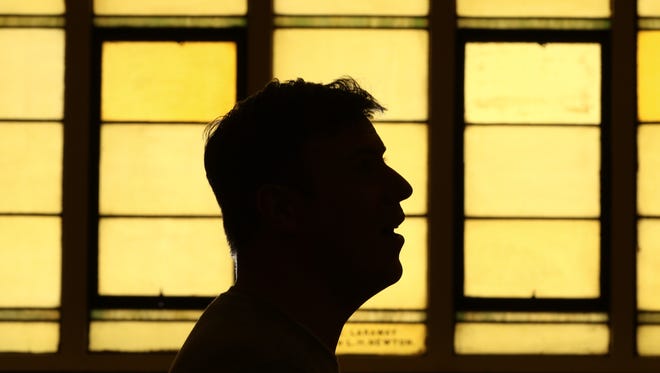 Campus pastor Chris Tillman is silhouetted against the stained glass windows at the new Downtown Mission Church in Stevens Point.