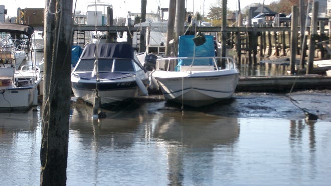 An extreme low tide leaves boats stuck in the mud at the Shark River Municipal Marina, where Neptune officials want the state to proceed with a long-awaited dredging project (file photo courtesy Philip Huhn/Neptune Township).