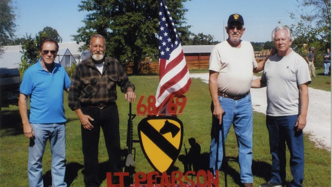 From left: Gary Pearson, Gary Vickers, Jessie Raley and Kenneth M. Pearson stand beside a memorial tribute Vickers built in honor of Pearson’s older brother, Francis L. Pearson, who died in Vietnam.