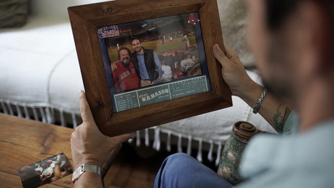 David Biller holds a photo of himself and his father on Friday, Sept. 18, 2020, at his apartment in Rio de Janeiro, Brazil. The photo is from when they watched the Red Sox beat the Yankees in the bottom of the ninth inning on Sept. 11, 2012, at Fenway Park, in Boston. One month later, the author moved to Brazil.
