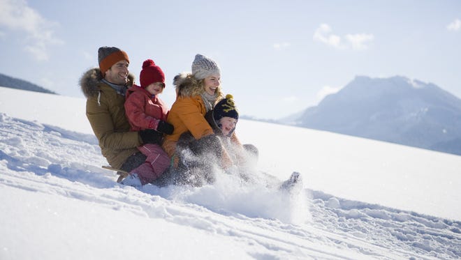 Family tobogganing on snow. Forecasters expect significant amount of snow from winter storm over the weekend.