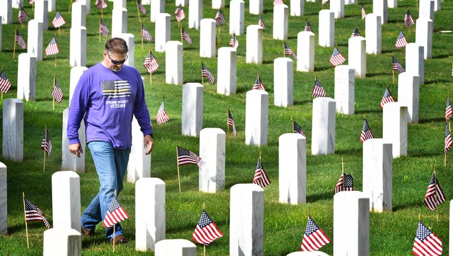 Marine veteran Frank Carter walks among tombstones and flags after he an other veterans and scouts put out flags for Memorial Day at Nashville National CemeterySaturday May 26, 2018, in Nashville, Tenn.