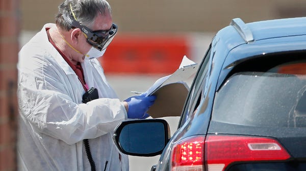A worker, wearing protective gear, checks in a per