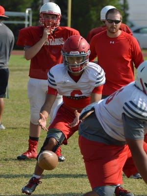 Sweetwater senior quarterback Chris Thompson, shown here taking a snap during practice on Tuesday, has quickly adjusted to the new offensive scheme implemented by first-year coach Ben McGehee (right background).