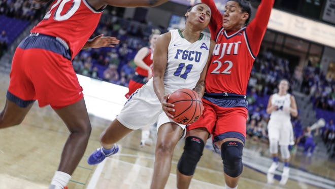 FGCUs Erica Nelson (11) pushes through NJIT's Danielle Tunstall (20) and Tatianna Torres (22) to attempt a layup at Alico Arena on Friday, March 2, 2018.