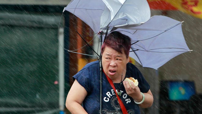 A woman struggles with her umbrella against powerful gusts of wind generated by typhoon Megi across the the island in Taipei, Taiwan, Tuesday, Sept. 27, 2016.