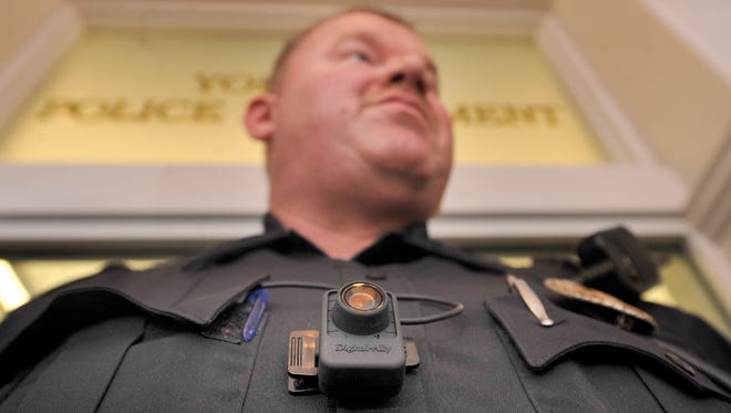 York City Police Officer James Knarr, wearing a body camera, listens to Chief Wes Kahley as he shares information about the new camera during a news conference at the police station on Tuesday. "We will be recording outside of residences." said Kahley in regard to the privacy of citizens and not video recording them in their homes.