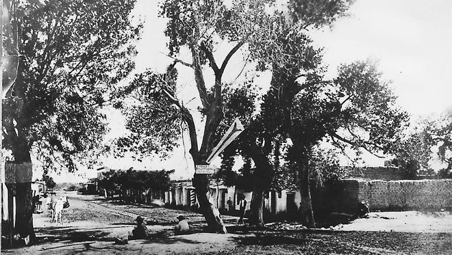 El Paso in 1880. At the far left is the original "newspaper tree" on the southeast corner of El Paso and San Francisco streets. (The sign on the cottonwood at center, on the acequia, says "Conklin's Real Estate Agency.")