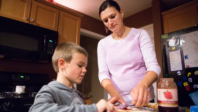 Laura Randall has help from her son Evan, 5, to prepare peanut butter and jelly sandwiches for lunch the next day.