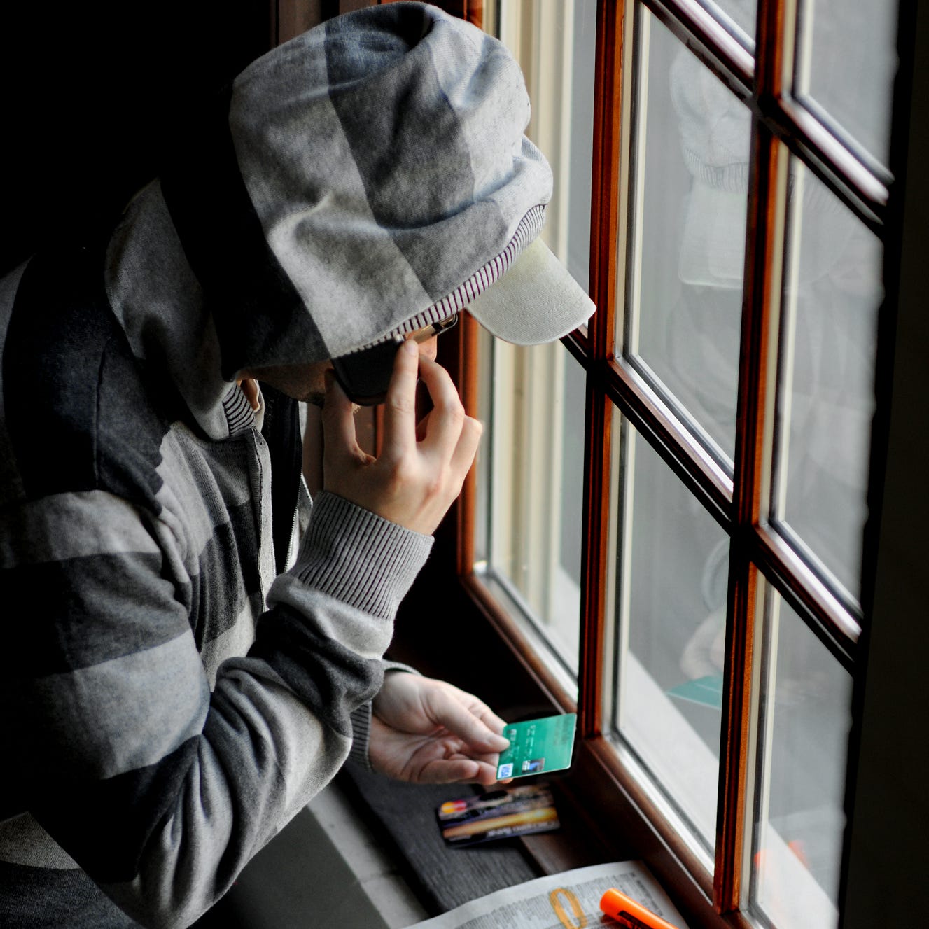 This photo illustration depicts a man as a scam artist using his cell phone to conduct an illegal enterprise.