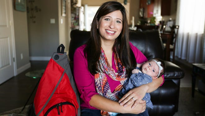 Jenni Worley holds her five-week-old daughter Kira as she sits next to her new 72-hour earthquake preparedness kit, supplied by the state Office of Emergency Management.