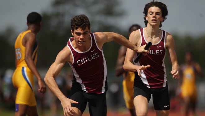 Chiles' Michael Phillips takes off on a 4x800 anchor leg after receiving the baton pass from brother Connor Phillips during the 2018 Chiles Track & Field Relays.