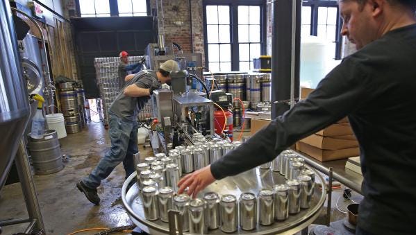 Indiana City Brewing Co. brewer Nick Shadle (right) takes cans of freshly filled beer off the conveyor to weigh at the Indianapolis brewery on Jan. 26, 2016.   iCan Solutions is a mobile canning company that serves local brewers.