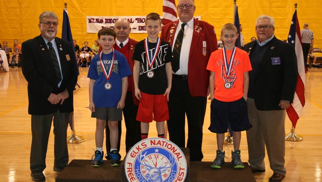 Colton Conkle (center) stands on a podium after taking first place in the Elks Hoop Shoot free throw contest in Angola, Indiana.