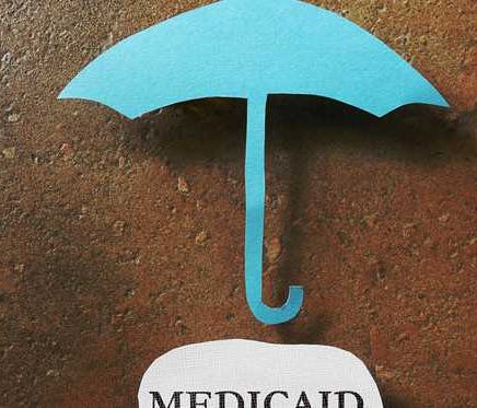 A paper umbrella above a piece of paper with Medicaid written on it.