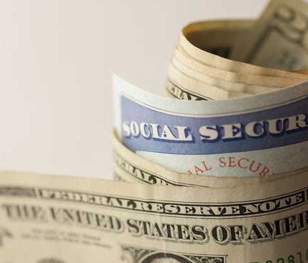 A Social security card rolled up in a wad of paper money.