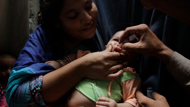 Pakistani mother holds her child as a health worker gives him a polio vaccine in Lahore, Pakistan, on Aug. 15, 2015.