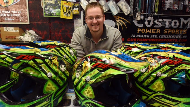 Donnie Inman stands with the helmets he helped customize for Custom Power Sports.