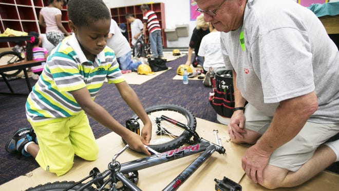 Volunteer, Ralph Jones and Zion Gilmer, 7, of Phoenix work on building his bike at the Build-A-Bike event at the I.G. Homes Branch of the Boys & Girls Clubs of Metro Phoenix on Saturday, May 16, 2015.
