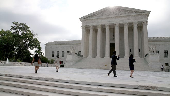 People gather in front of the Supreme Court Building June 18, 2015 in Washington, DC.