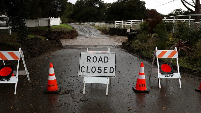 Signs block a road that is overcome with floodwaters during a rain storm on January 23, 2017 in Santa Clarita, California.