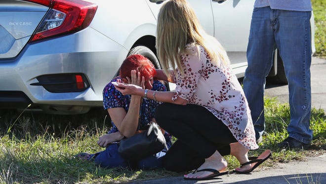 A woman consoles another as parents wait for news regarding a shooting at Marjory Stoneman Douglas High School in Parkland, Florida, Wednesday. The suspect, Nikolas Cruz, 19, has been charged with 17 counts of premeditated murder.
