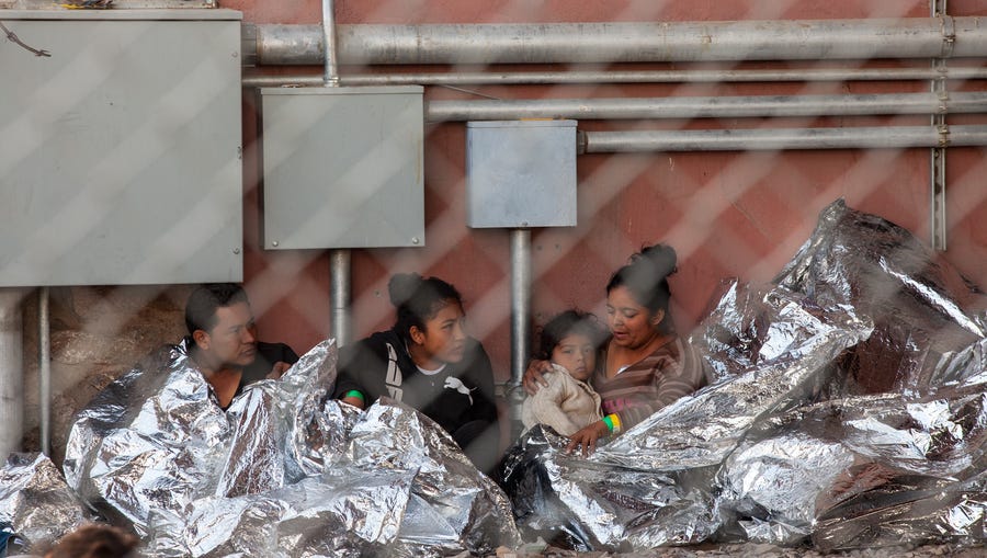 Migrants held in temporary fencing underneath the Paso