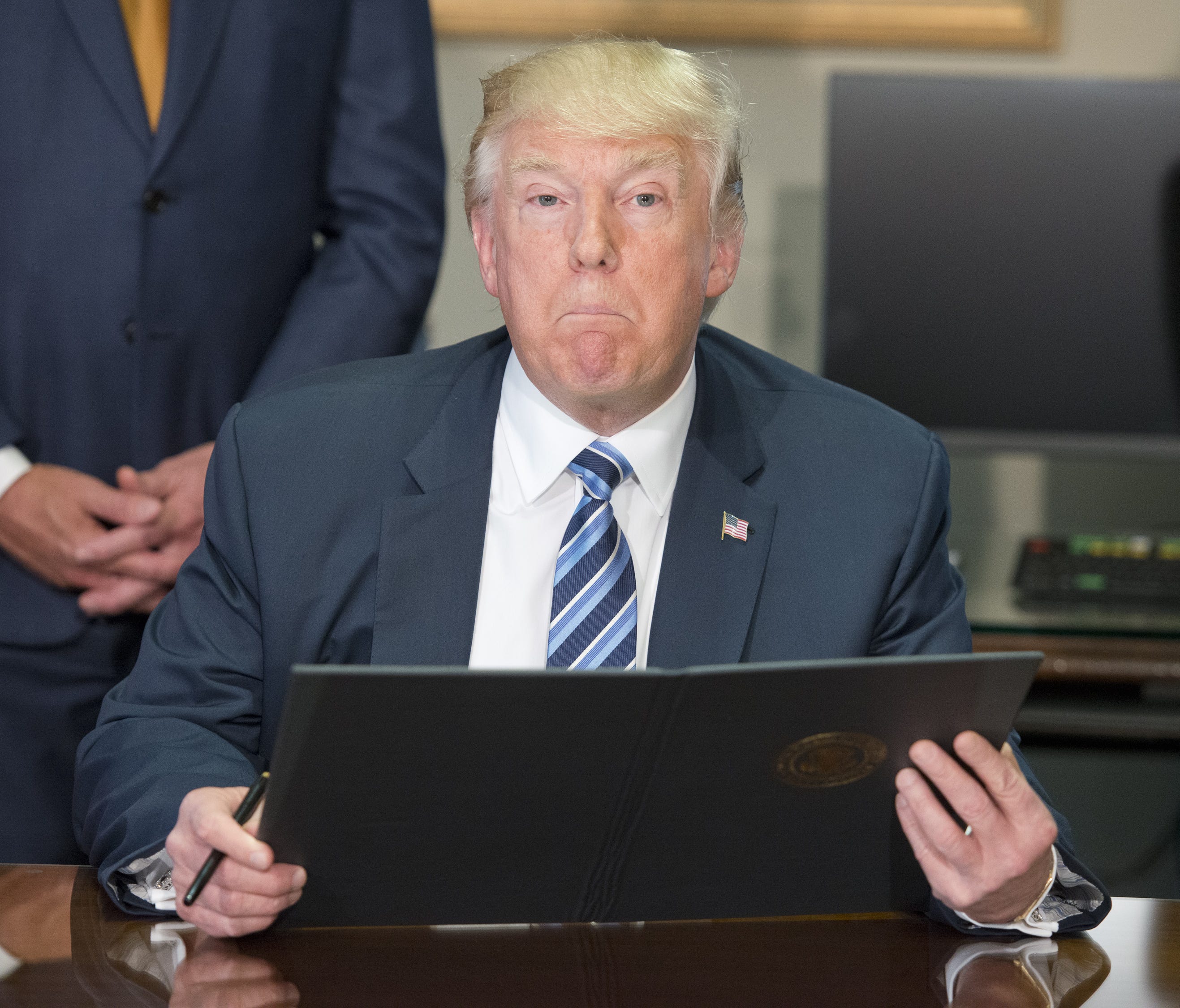 President Trump looks over the first of three executive orders concerning financial services at the Department of the Treasury April 21.