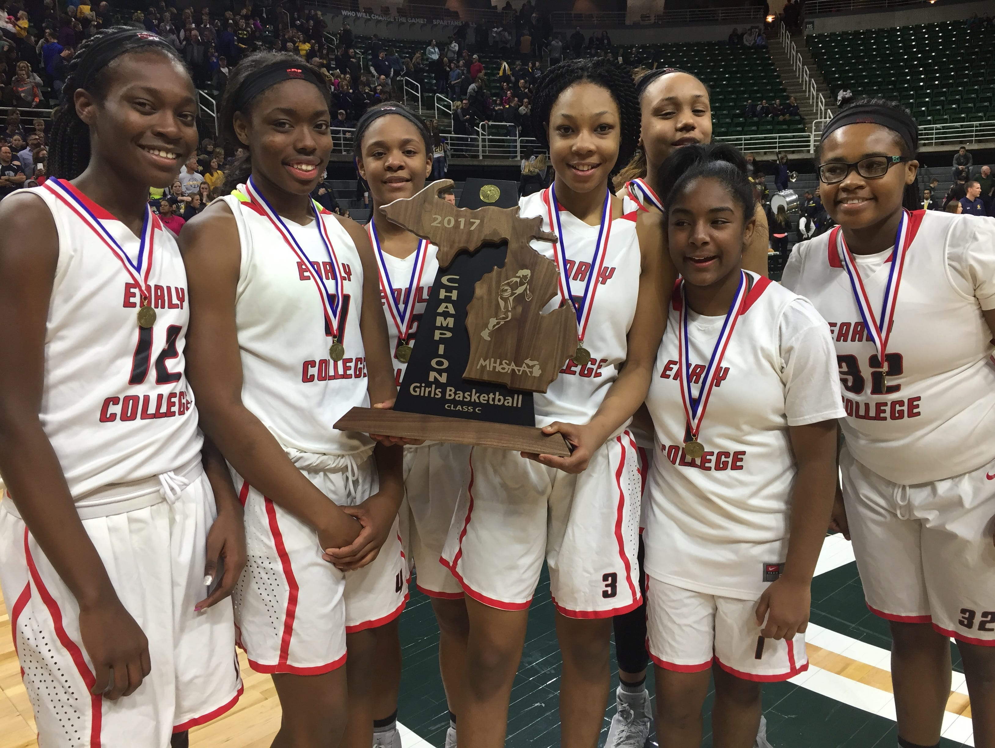 Detroit Edison freshman Gabrielle Elliott, joined by teammates, holds the Class C girls basketball state trophy after her team's 46-44 win over Pewamo-Westphalia at the Breslin Center on Saturday, March 18.