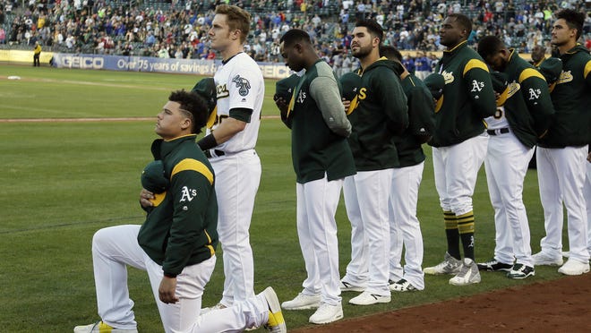 FILE - In this Sept. 23, 2017, file photo, Oakland Athletics catcher Bruce Maxwell kneels during the national anthem before the team's baseball game against the Texas Rangers in Oakland, Calif. Maxwell is the only major leaguer to take a knee during the playing of "The Star-Spangled Banner" before a game. Major leaguers have not, in general, been the first set of players in pro sports to speak out on issues of social injustice. We'll see what stances they take on and off the field when games return.