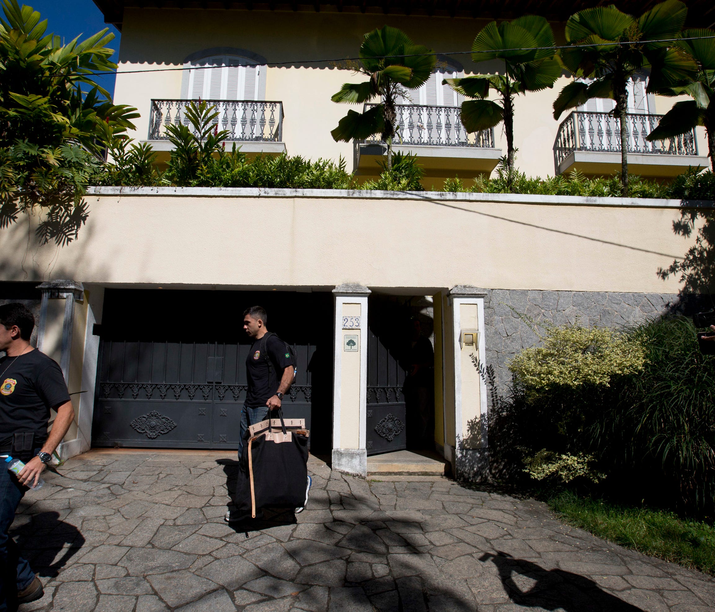 A Federal Police officer carries a bag filled with items confiscated from the home of Carlos Nuzman, president of the Brazilian Olympic committee, Tuesday, Sept. 5, 2017, in Rio de Janeiro, Brazil. Federal police searched Nuzman's house Tuesday morni
