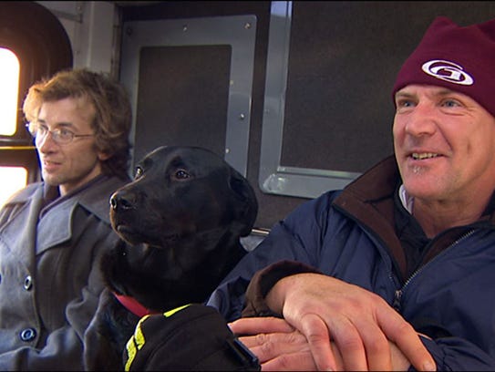 Eclipse, a black Labrador, with owner on bus.