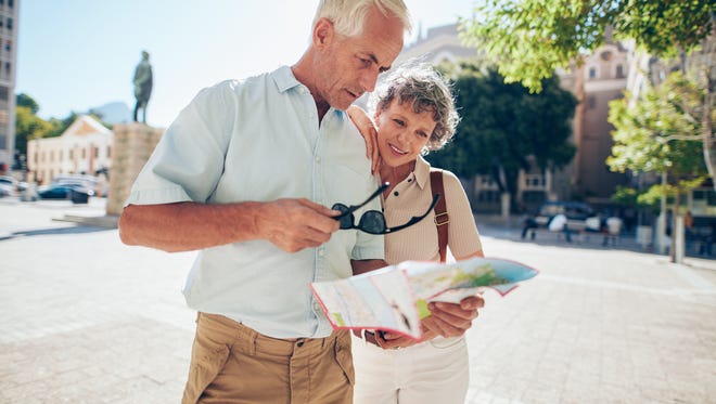 Mature couple standing outdoors in the city looking at a map. Senior man with his wife using city map for finding their location.